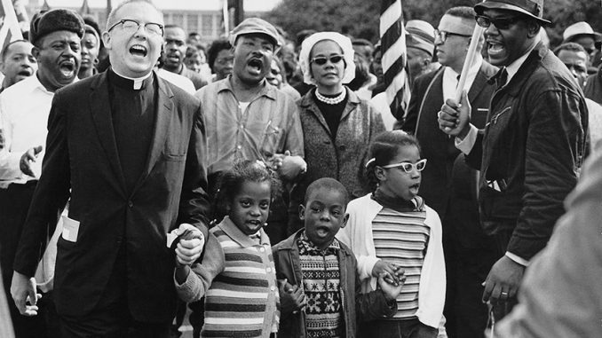 martinlutherkingjr_selmamarch_wc_web120 Dr. Martin Luther King, Jr., was a champion for equity in education. Civil Rights Movement co-founder Dr. Ralph David Abernathy and his wife Mrs. Juanita Abernathy (not pictured) follow with Dr. and Mrs. Martin Luther King, Jr., as the Abernathy children march on the front line, leading the Selma to Montgomery March in 1965. The children are (left-right): Donzaleigh Abernathy in striped sweater, Ralph David Abernathy III, and Juandalynn R. Abernathy in glasses. Name of the White Minister in the photo is unknown. (Abernathy Family Photos/Wikipedia Commons)
