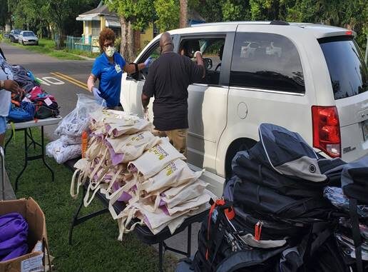 Shown are Maria Sampson and Brent Woods loading up a patron's car with book bags and groceries.