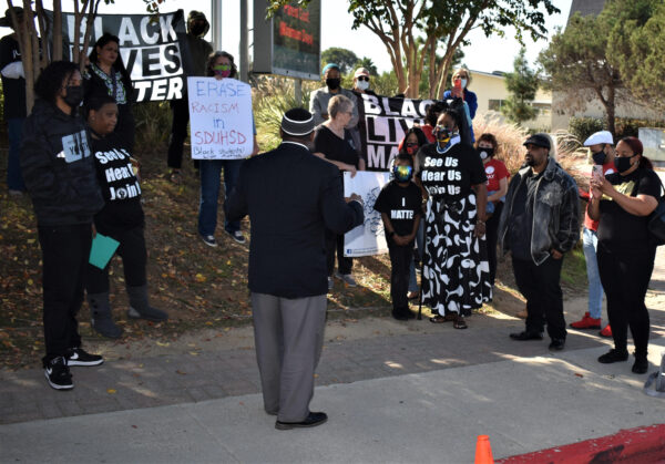 Yuseff Miller with No. County Equity and the Justice Coalition speaks with his back to the crowd.