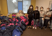 Members of the Hope Street Margolis Family Center, the Assistance League of Los Angeles pose next to the donated backpacks in the facility's library. Credit: assistanceleaguela.org