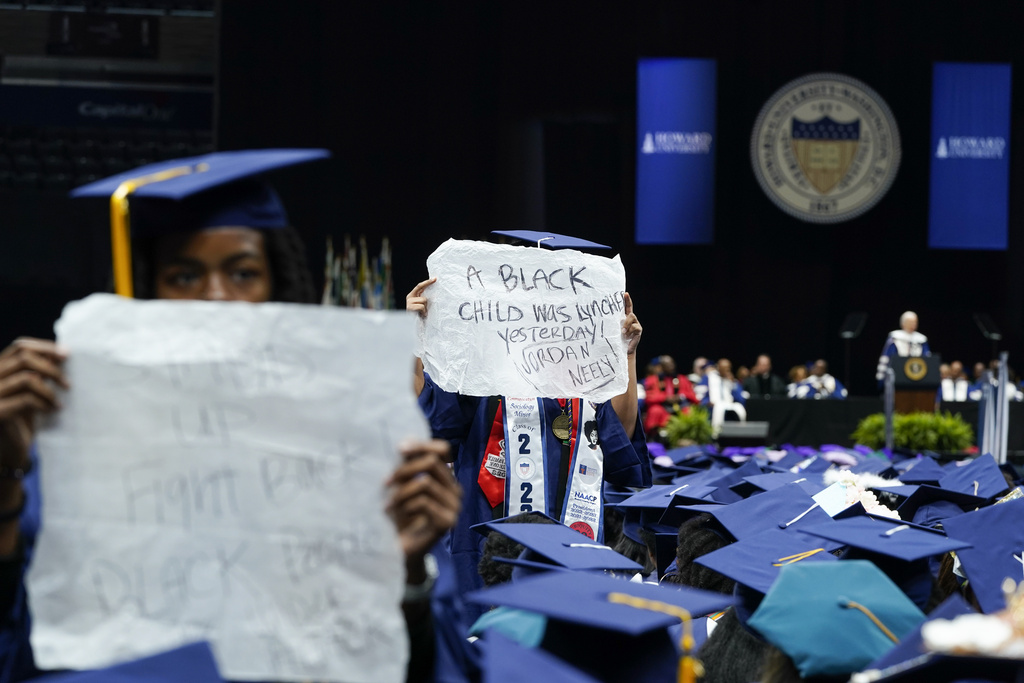 Graduates hold signs reading “A Black child was lynched yesterday! Jordan Neely” and “Stand up, Fight Back, Black People Under Attack” as President Joe Biden, right, speaks at Howard University’s commencement in Washington, Saturday, May 13, 2023. (AP Photo/Alex Brandon)