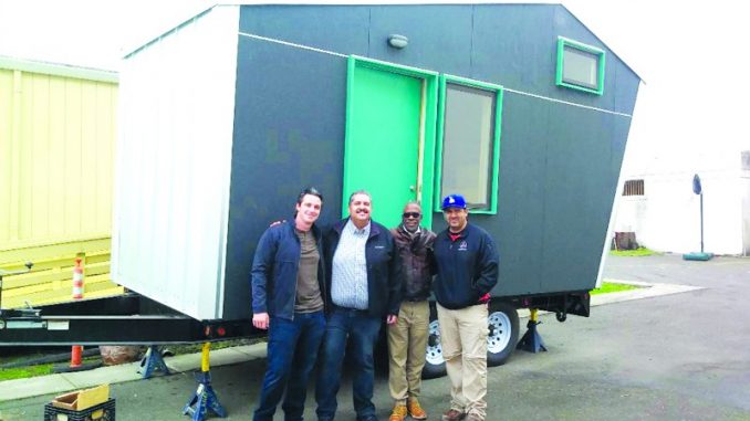 Pocket-Homes-1-1 Truck driver Martin Kauffman (far left) and electrician Art Ramirez (far right), who both donated their services to deliver Laney College’s tiny home prototype to West Side Missionary Baptist Church, stand in front of the Pocket House Model M with Rev. Ken Chambers (middle right) and Councilmember Abel Guillén (middle left).